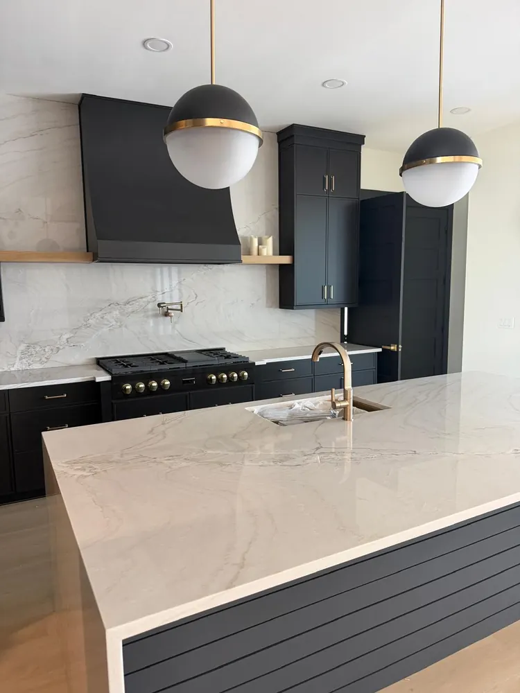Black kitchen with island and stone backsplash by Braga Remodeling